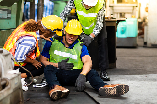 Injured worker in PPE sitting on the floor