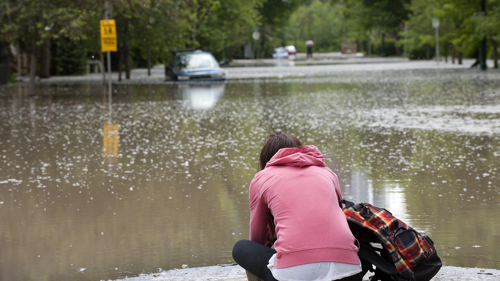 person stiing on high ground looking at flooded street
