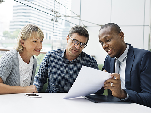 Insurance agent reviewing a form with a middle-aged couple. The agent looks like he enjoys his job in insurance.