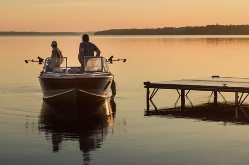 A boat to fish and ski tied to a dock. The owner is thinking about buying boat insurance for liability coverage.