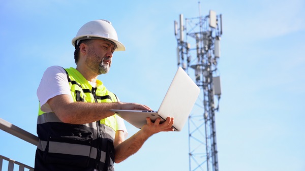 Communication tower and a worker in a hard hat and safety vest