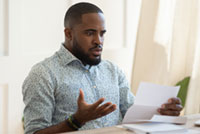 Man holding bill, looking frustrated