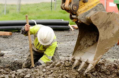 Construction worker in a hole with a shovel