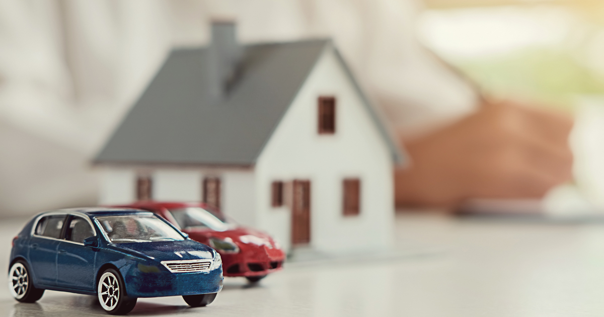Two cars parked outside a home. Auto and home insurance agent sitting at a desk.