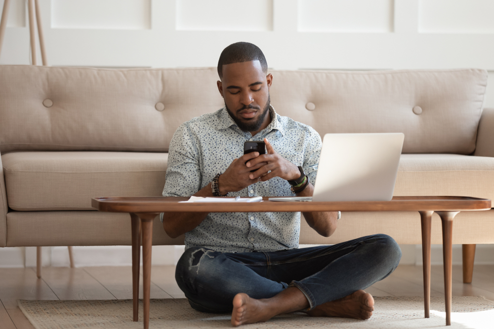 Ergonomics for working at home - man sitting on the floor using a laptop on the coffee table