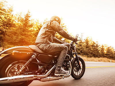 A person riding a motorcycle on a road. Do motorcycles need to be insured?