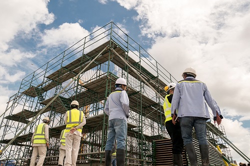 Construction workers next to rows of scaffolding
